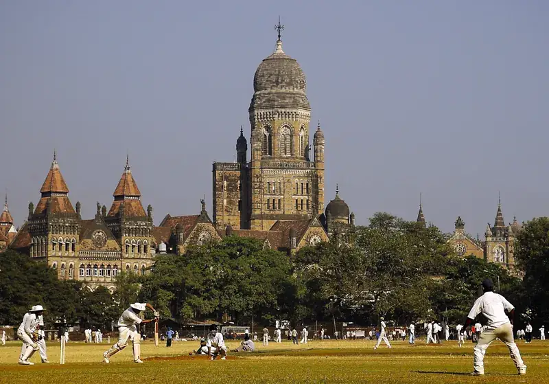 Men playing cricket on a maidan in Mumbai.