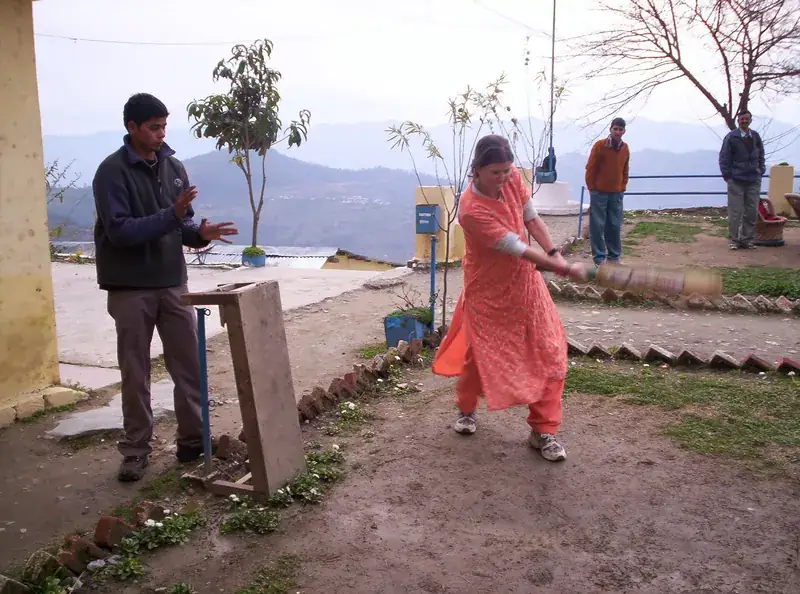 A woman batting in a hill-town cricket game.